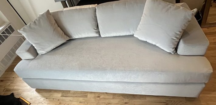 A light grey sleeper sofa rebuilt and placed in an apartment living room