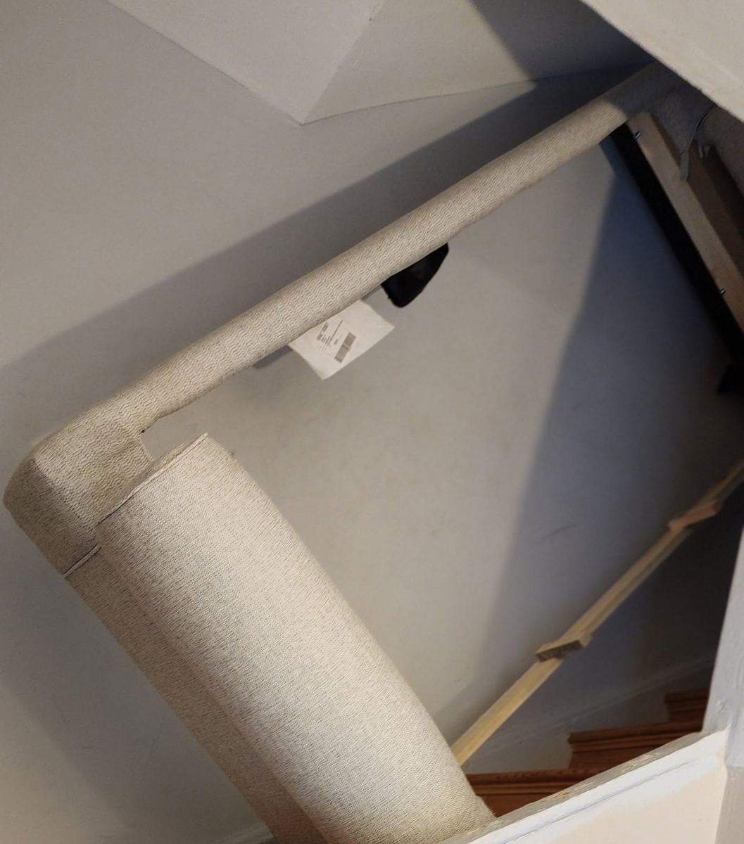 A sofa section being carried through a narrow stairwell