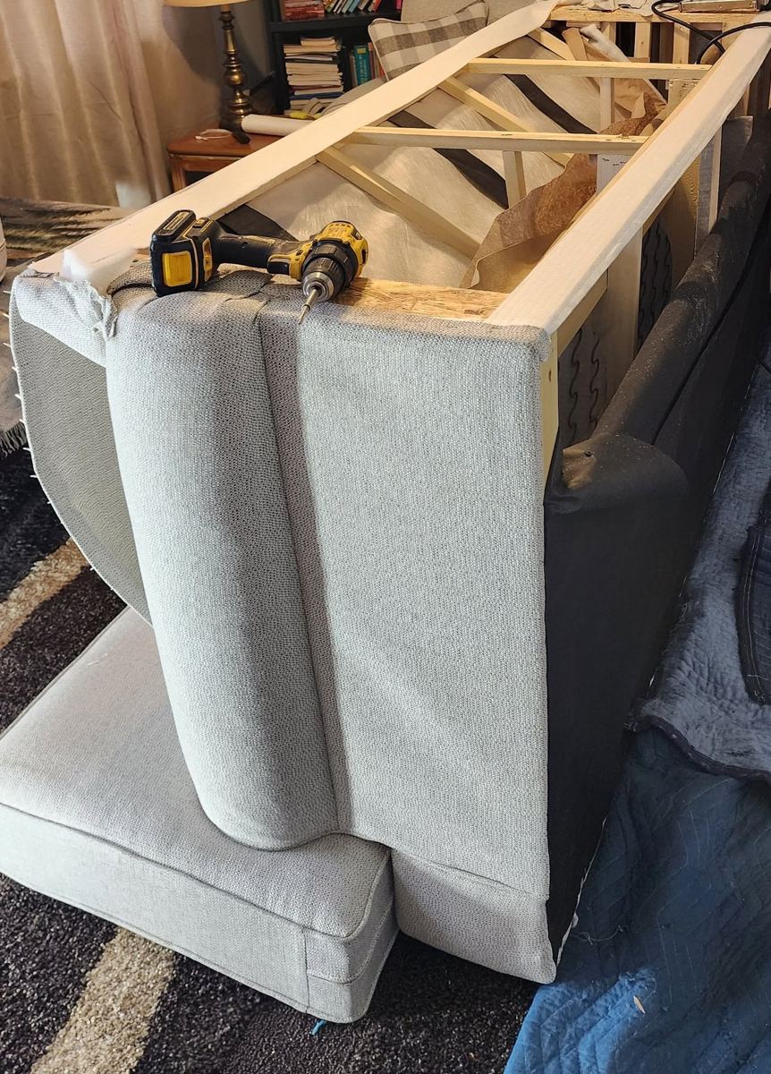 Sofa stood on end with the back upholstery opened, exposing the wood frame