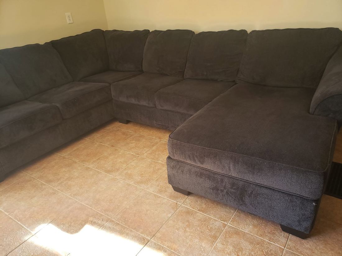 Charcoal fabric sectional with a chaise end arranged along two walls on a tiled floor