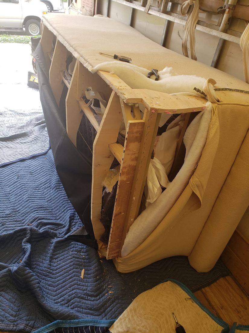 Cream sofa with one end opened, showing plywood frame panels, white padding and folded fabric, on blankets