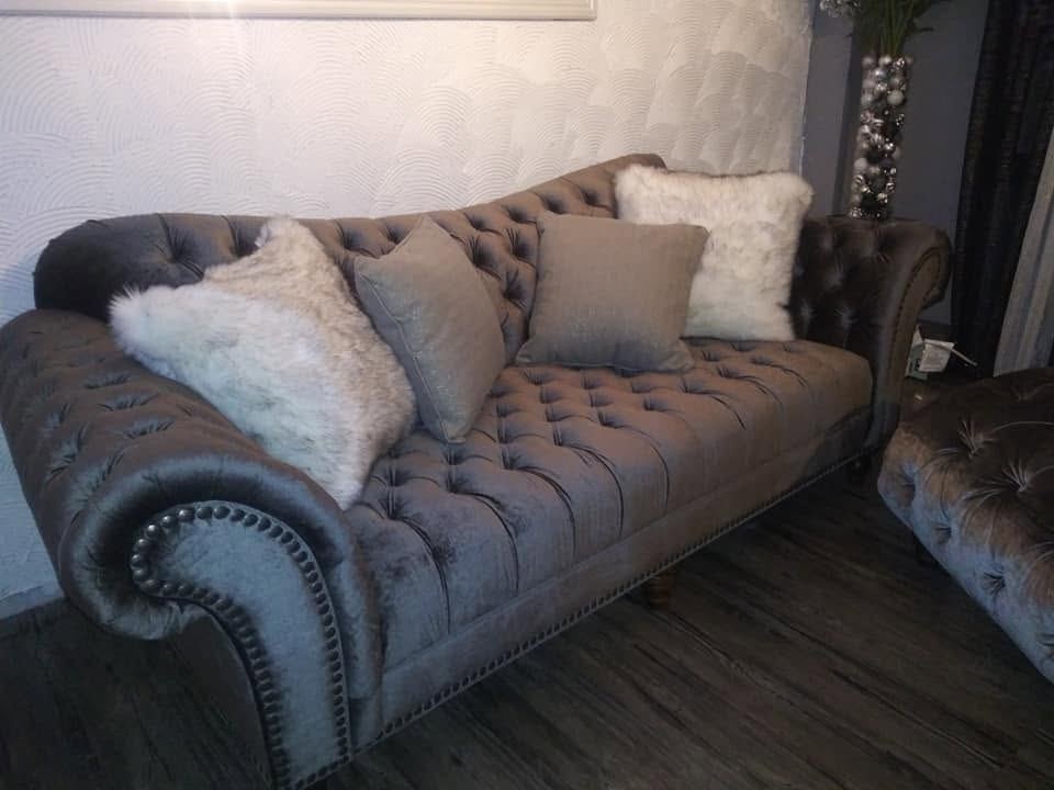 Grey velvet chesterfield sofa with deep button tufting, rolled arms with nailhead trim and fluffy white pillows