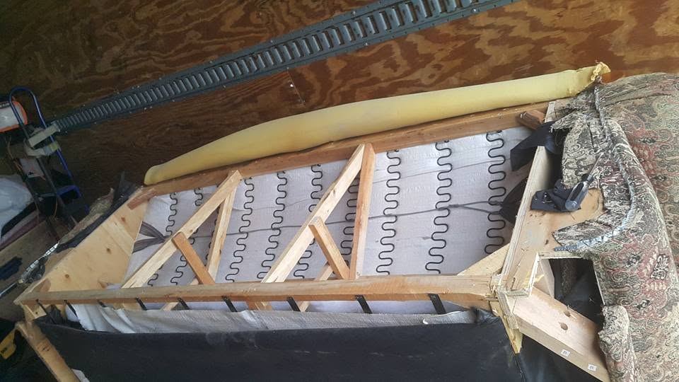 Close-up of an opened sofa frame with wooden cross braces over rows of zig-zag springs, paisley fabric at one end