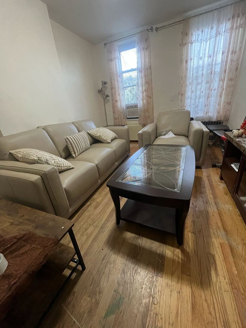 Taupe leather three-seat sofa and matching armchair around a glass-top coffee table on a hardwood floor